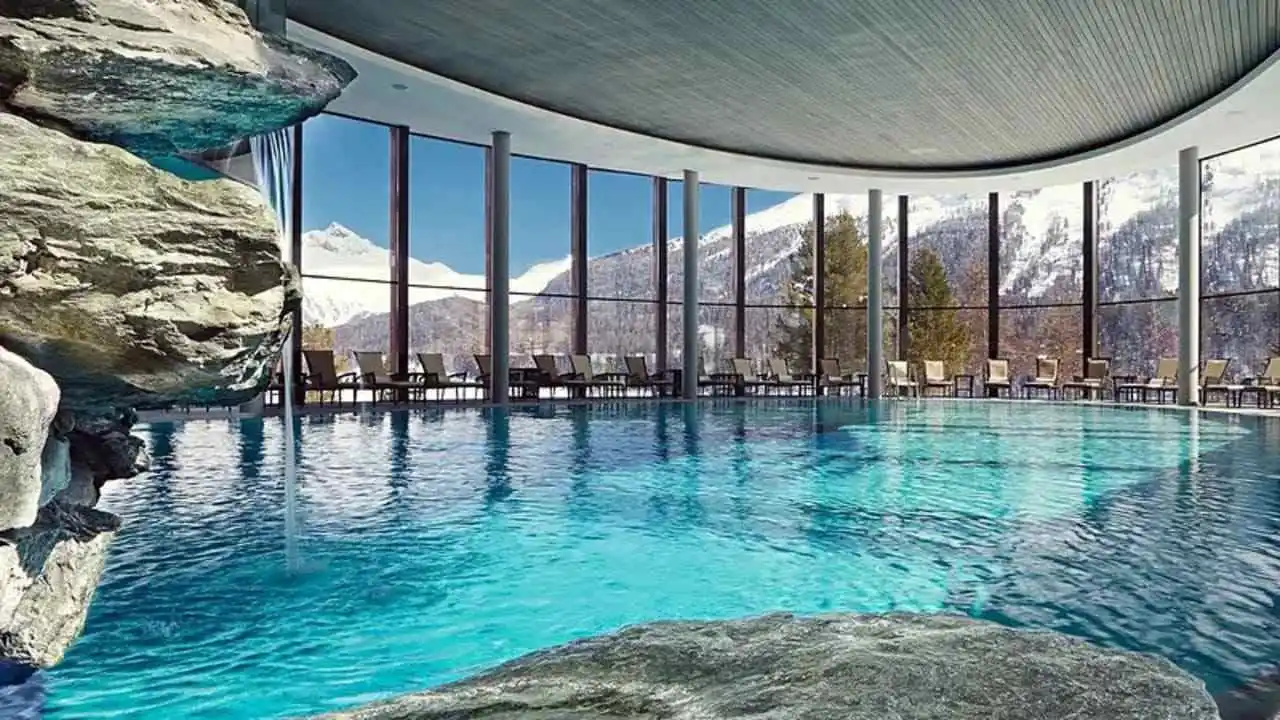 Piscina cubierta de lujo con grandes ventanales, rodeada de formaciones rocosas y con vistas