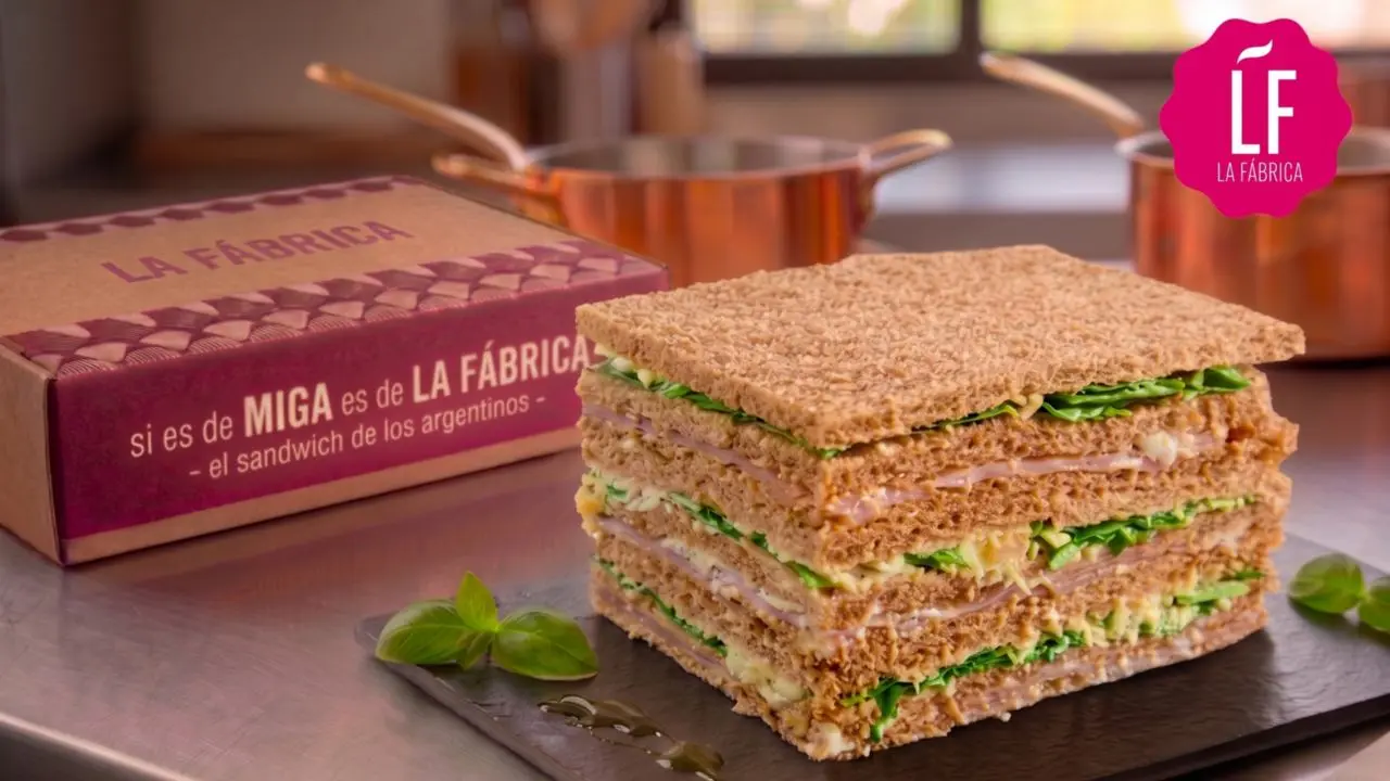 Sandwiches de miga de pan integral de La Fábrica y una caja con la marca de la compañía detrás