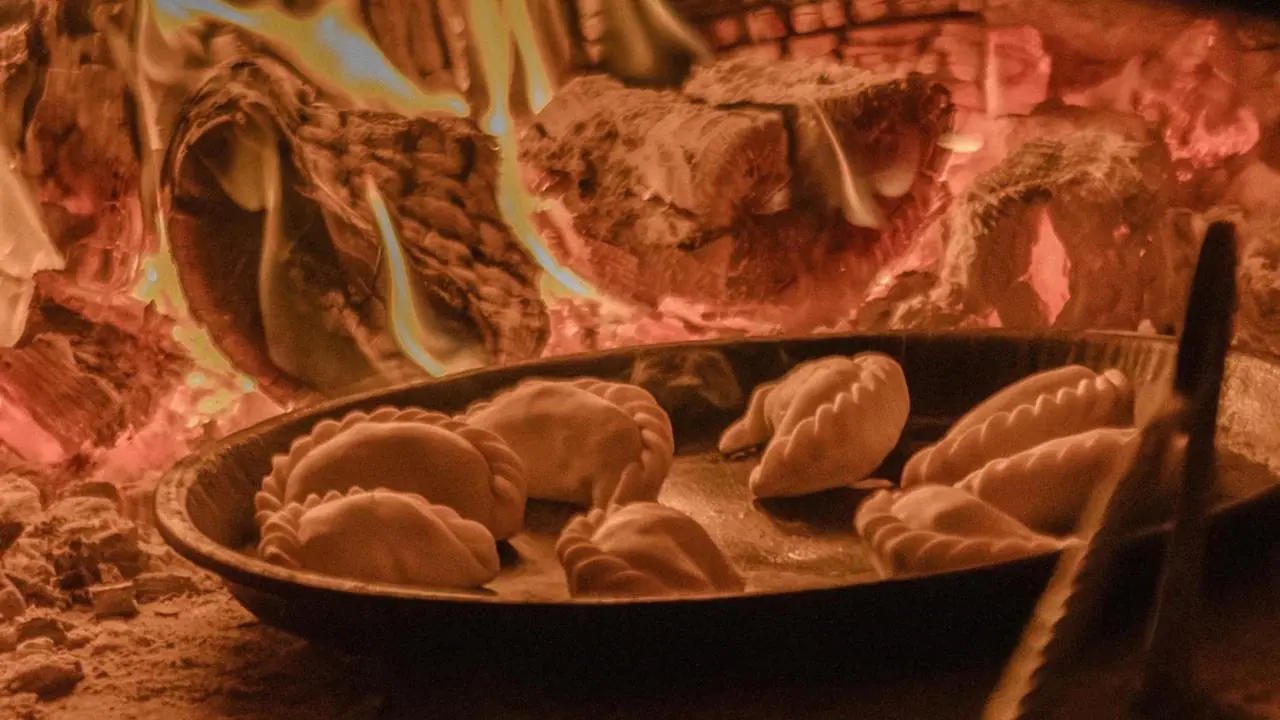 Empanadas horneándose a fuego directo en horno de leña