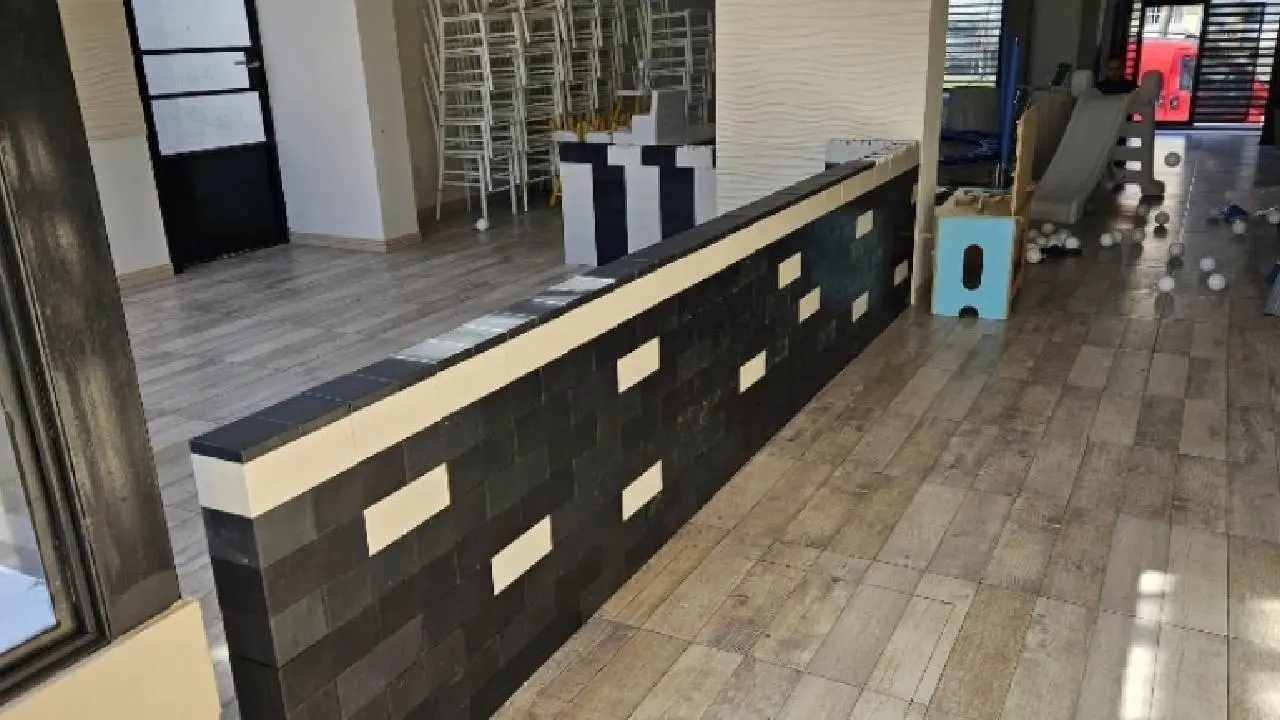 Interior de un salón con un división construida con ladrillos sustentables de color negro y blanco
