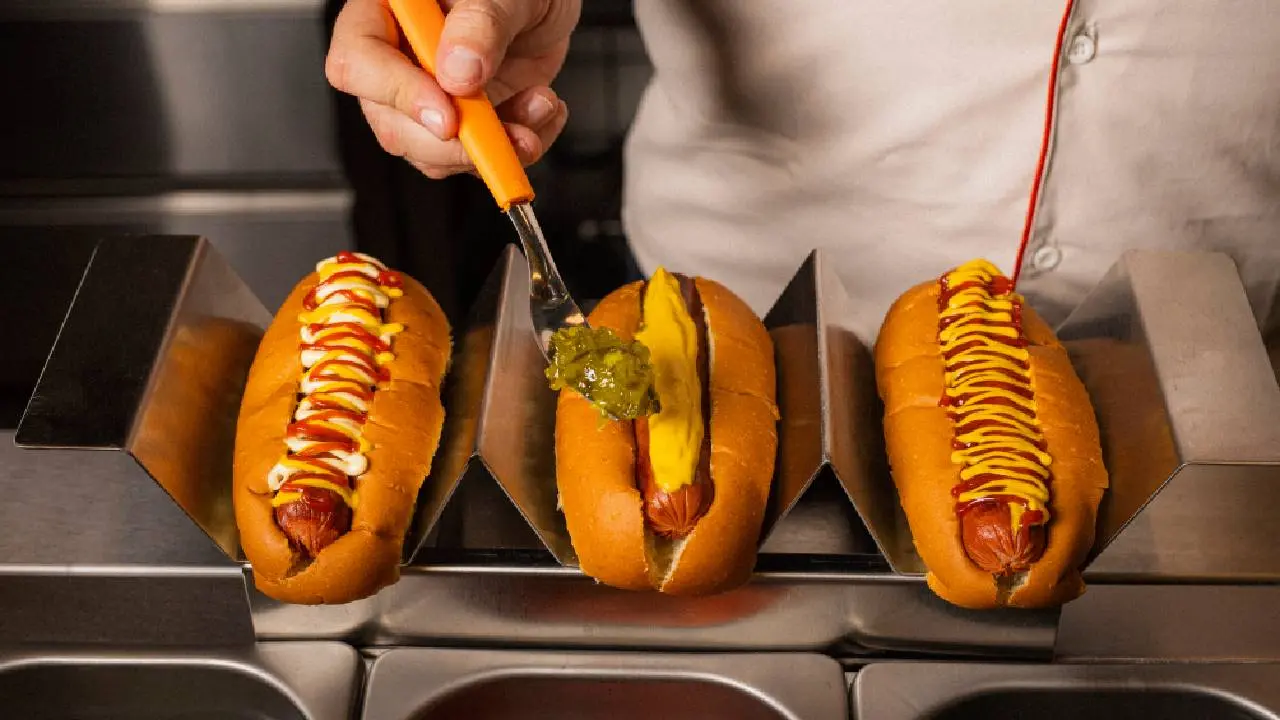 Tres panchos con distintas salsas y condimentos en su parte superor