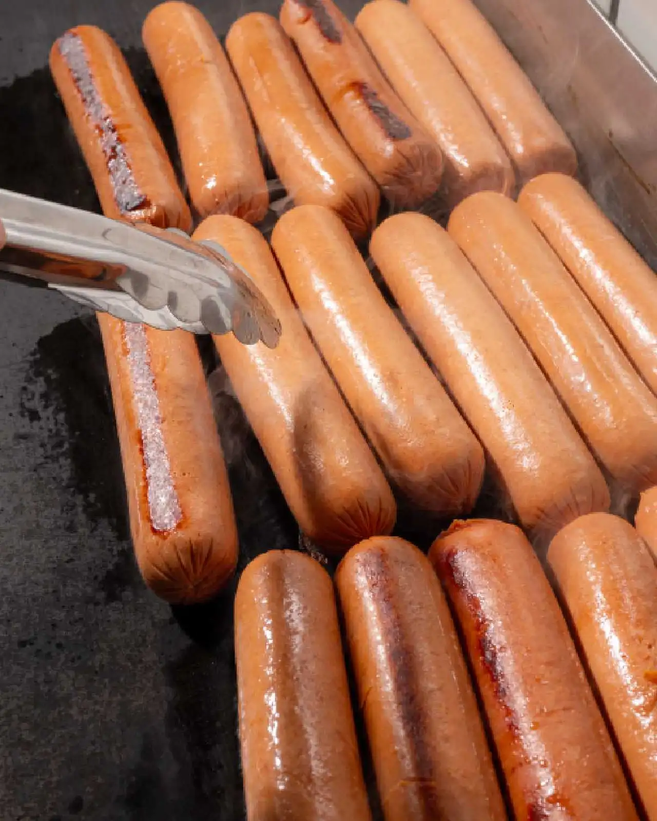 Salchichas arriba de una plancha cocinándose