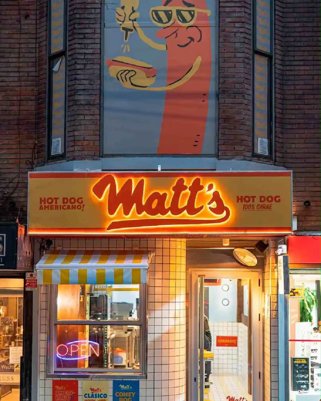 Frente del nuevo local de la panchería Matt´s iluminado