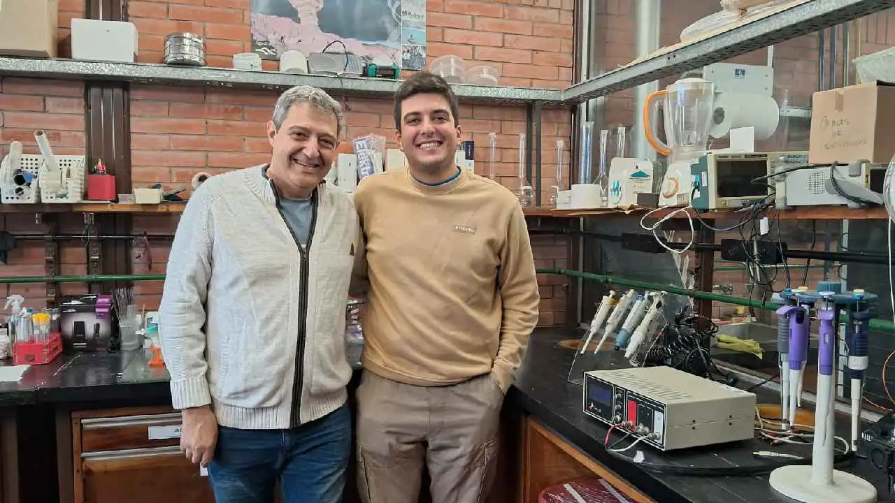 Los científicos Ricardo Negri e Ignacio Argento en su espacio de trabajo rodeados de distintos elementos que utilizan para reciclar baterías