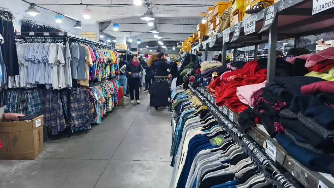 Pasillo central de un local de indumentaria Puro Hilo con percheros de ropa a ambos lados y clientes recorriendo el salón