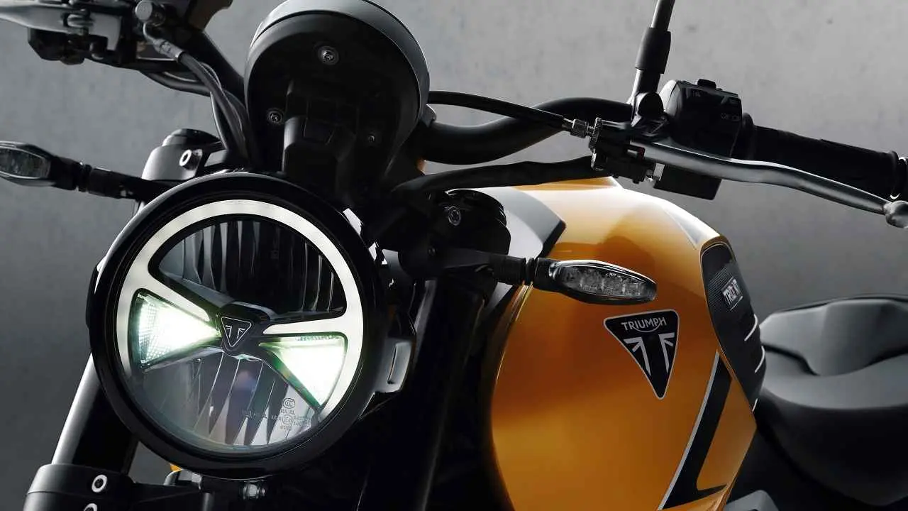 Primer plano del faro delantero LED redondo y el tanque de combustible amarillo de una motocicleta Triumph Trident