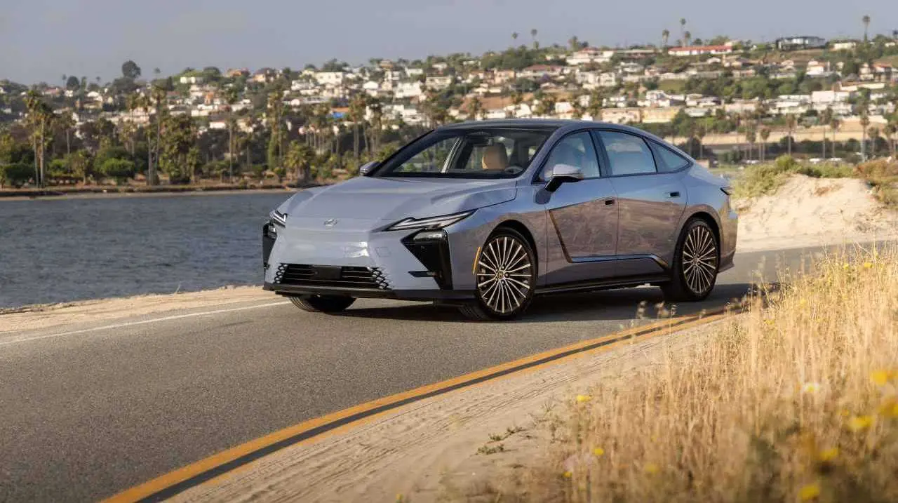 AUTO LEXUS EN UNA RUTA CON UN RIO DE FONDO Y PASTO