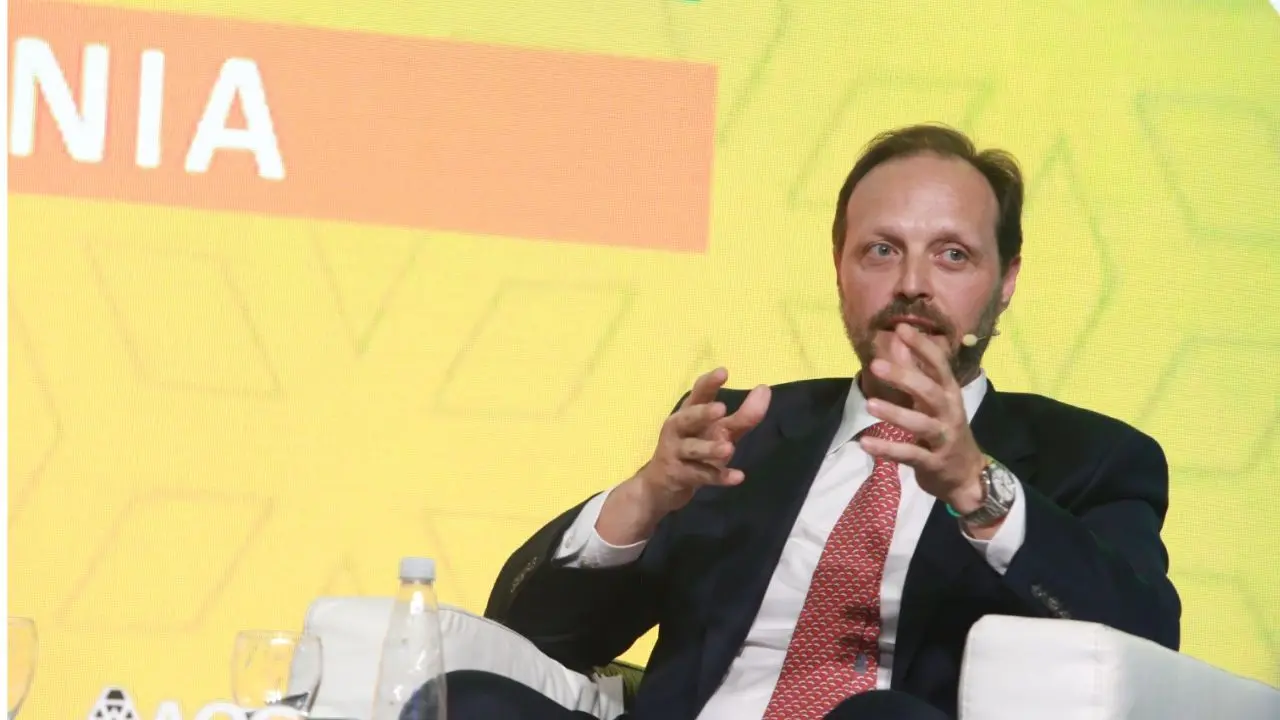 Sergio Mengoni CEO de TotalEnergies sentado en un sillón blanco con un fondo amarillo
