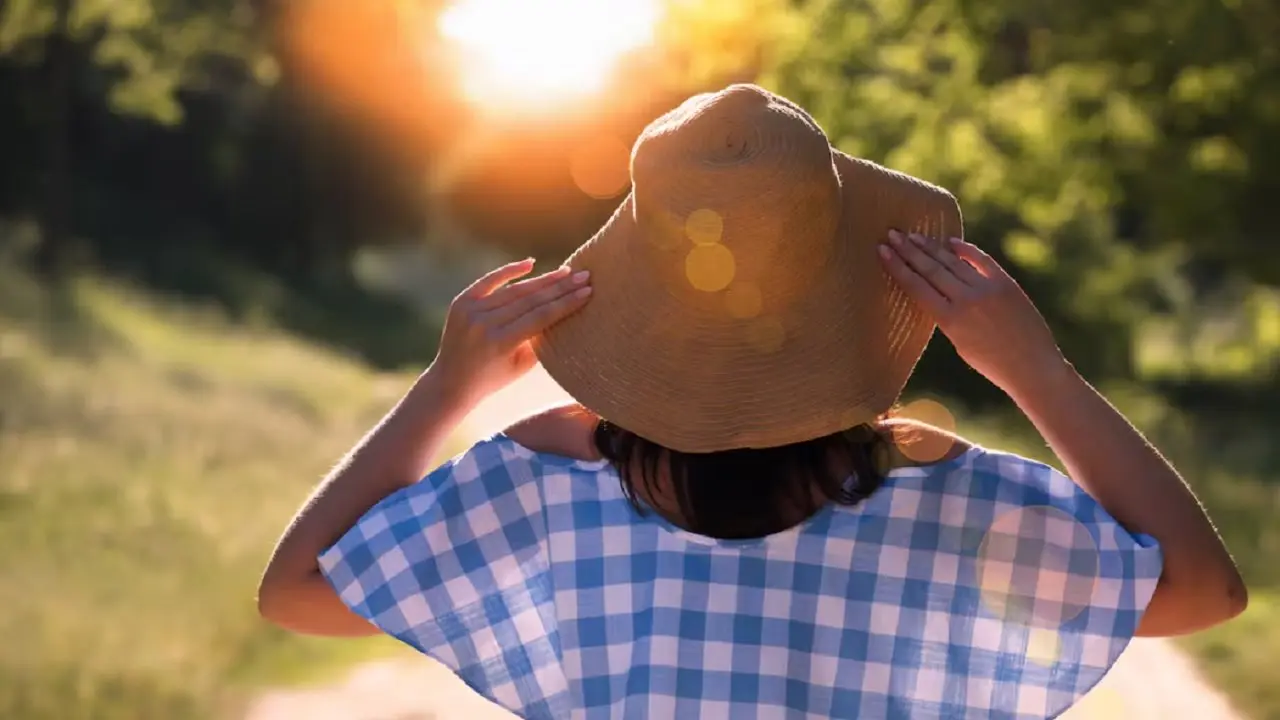 Una mujer con un sombrero al aire libre tomando sol