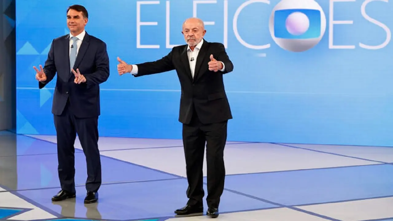 Luiz Inácio Lula da Silva y Flávio Bolsonaro parados en un estudio de televisión antes de empezar el debate