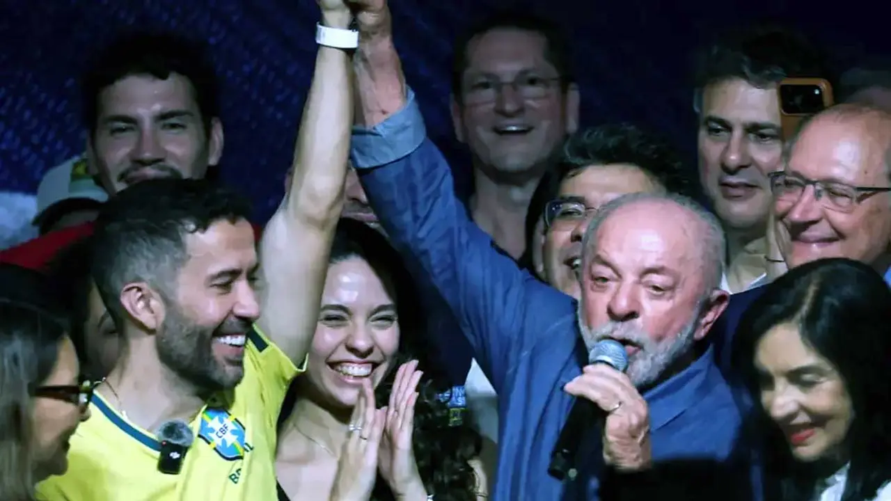 André Janones junto a Luiz Inácio Lula da Silva saludando a simpatizantes en un acto de campaña política en 2026
