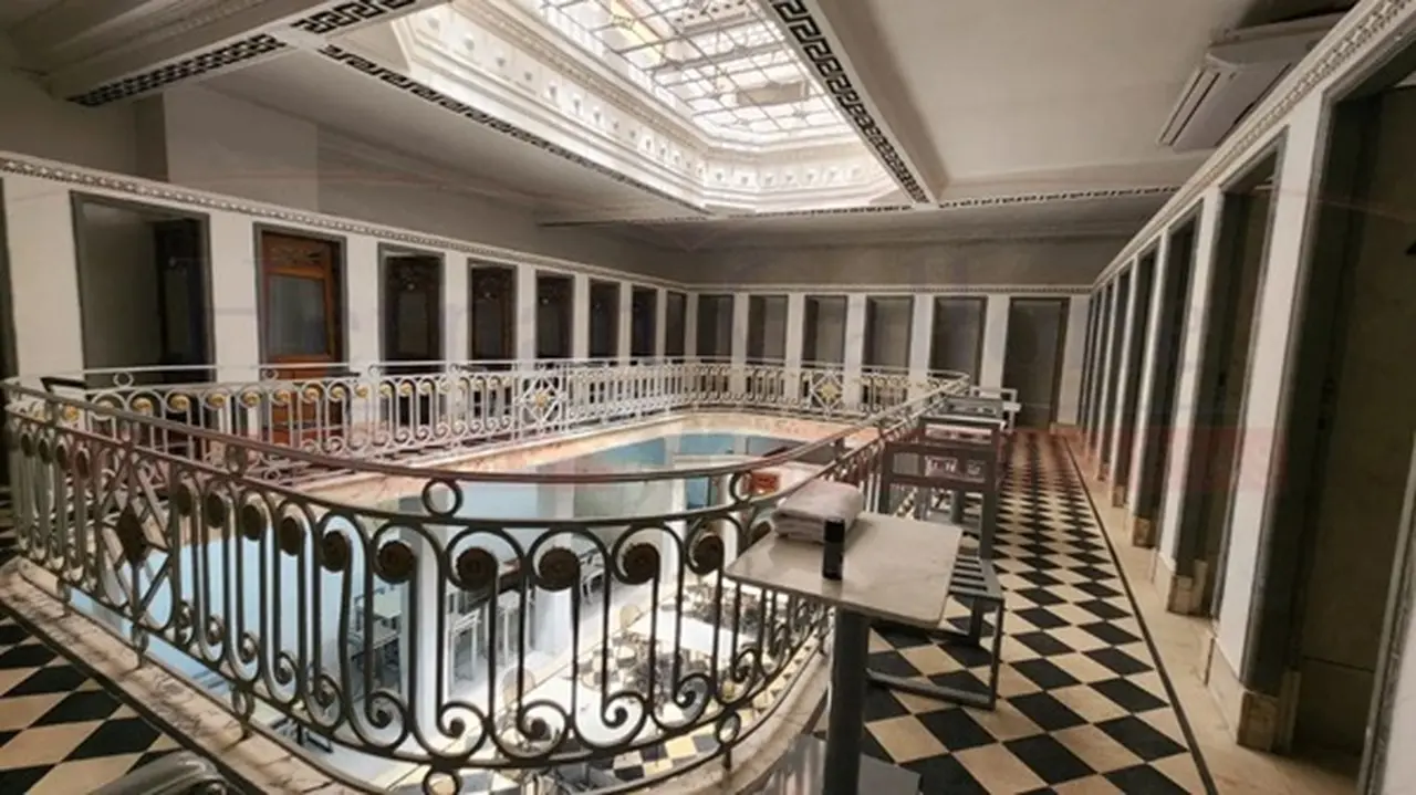 EDIFICIO ANTIGUO CON PISO CRUDO Y NEGRO Y REJAS NEGRAS CON UN TECHO DE VITRAUX