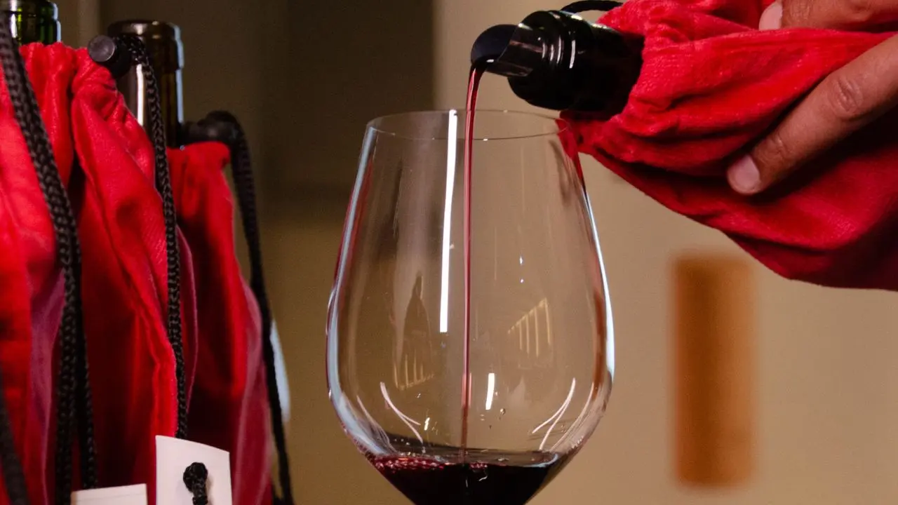 Una persona sirviendo un vino en una copa, cubierto por un paño. Imagen oficial