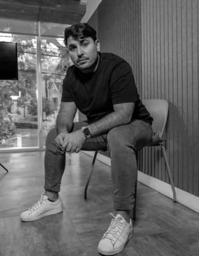 Kevin Jaimovich, creador de Cubelo, sentado en una silla en una habitacón. Foto en blanco y negro