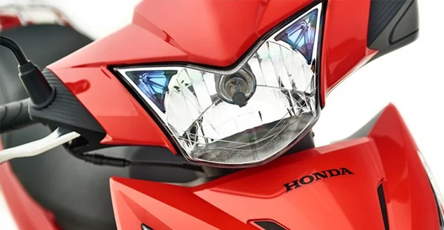 Imagen de la parte superior de una moto roja Honda Wave roja, que incluye parte del manubrio, luz frontal y el nombre de la marca