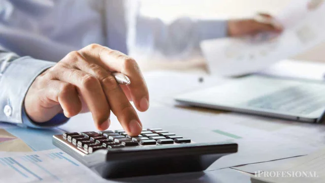 Una persona usando una calculadora y una computadora con papeles