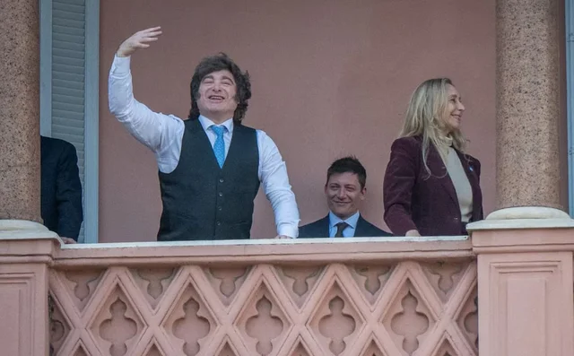 Javier Milei saluda desde el balcón, con Karina Milei a su lado y Santiago caputo atrás