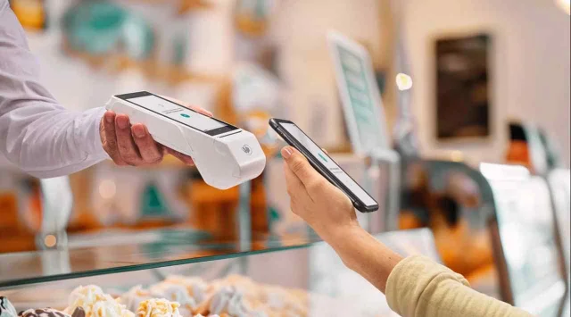 Una persona pagando con NFC desde su celular en un comercio