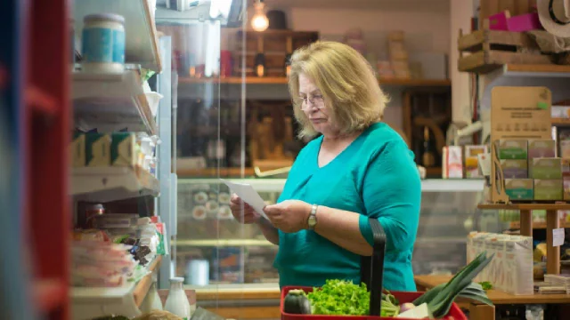 persona observa un papel frente a una góndola de supermercado
