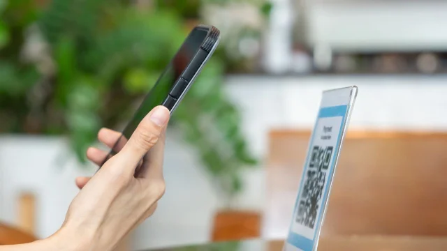 Una persona apunta su celular a un QR para realizar un pago