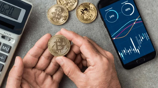 Usuario tiene un bitcoin en la mano, con un celular que sigue las cotizaciones y una calculadora
