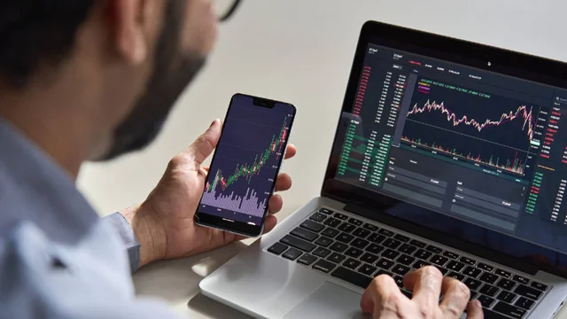 Inversor consulta en su PC y celular la cotización de Bitcoin