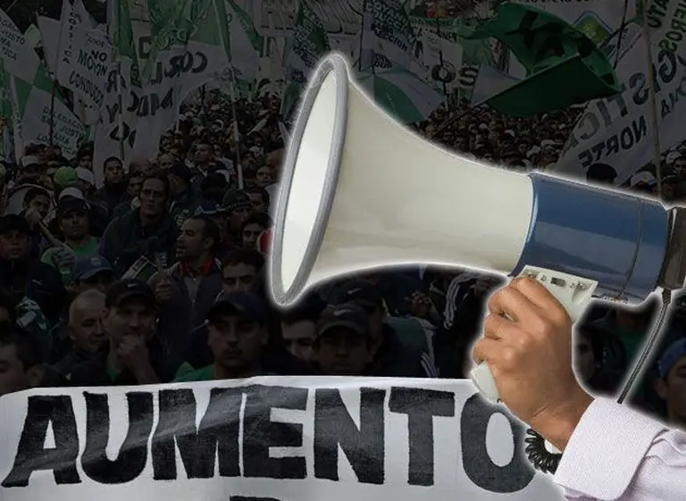 Megáfono sobre un cartel con la leyenda 'Aumento' sobre un fondo que muestra una manifestación sindical