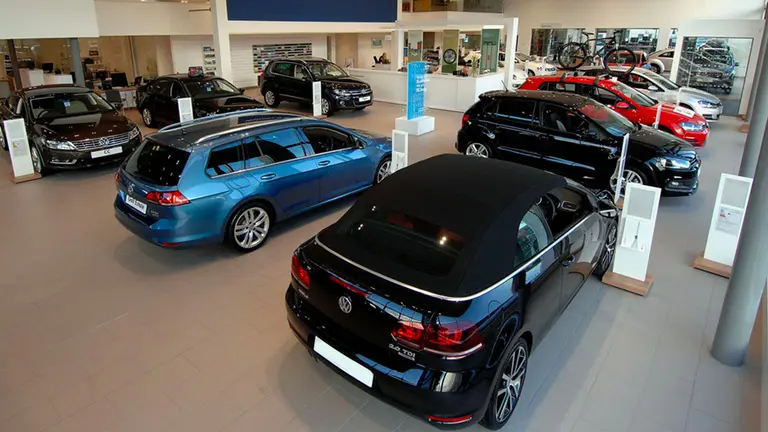 Autos y camionetas de distintos colores exhibidas en el interior del salón de una concesionaria