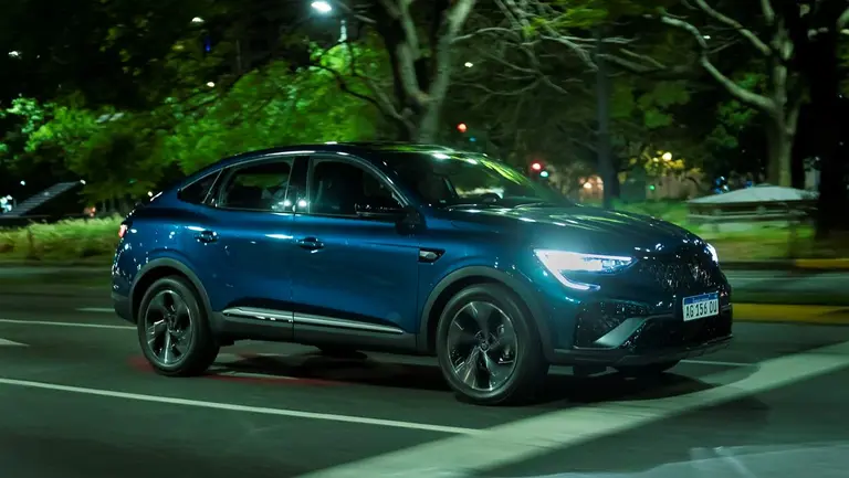 Renault Arkana azul de perfil sobre calle con árboles.