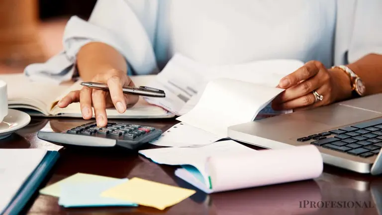Mujer con lapicera, calculadora, computadora y varias facturas