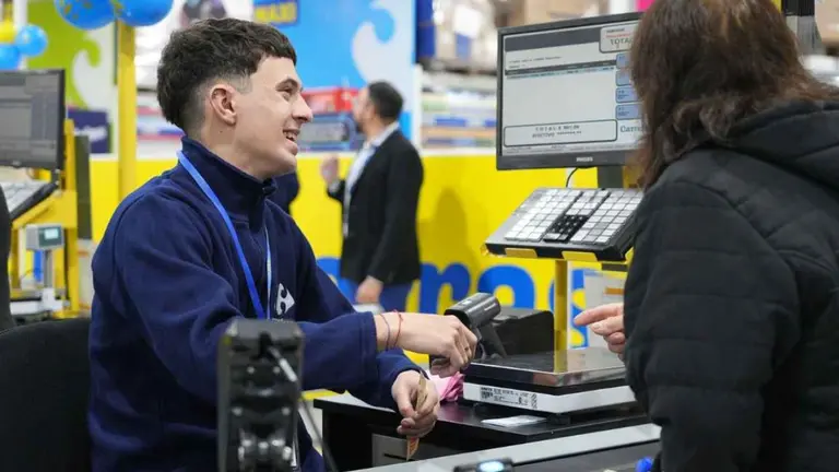 Cajero de un supermercado Carrefour atendiendo a un cliente. Sueldo empleados de comercio. Foto archivo