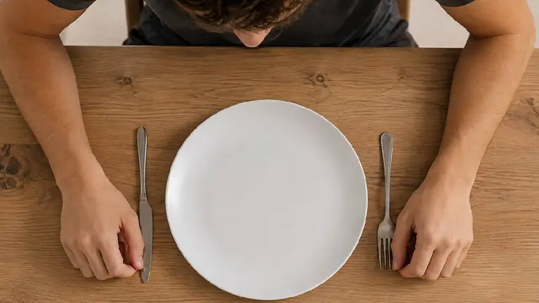 Imagen de un plato vacío y una persona frente a él. Imagen generada con IA