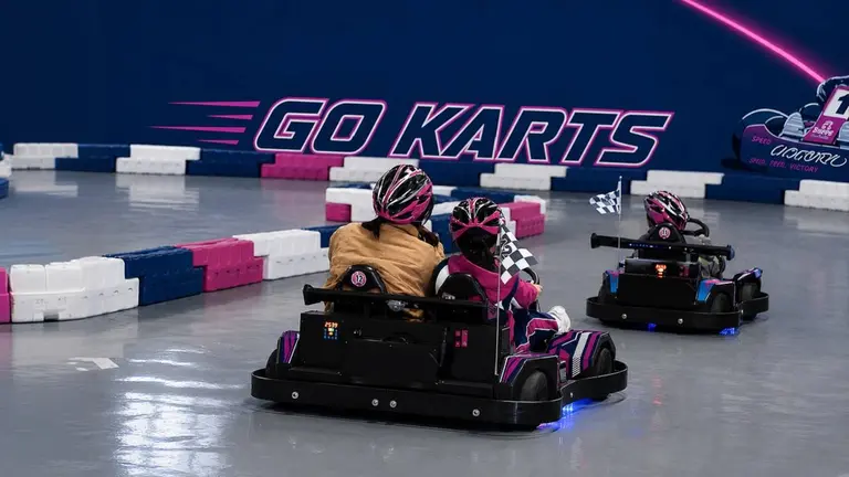 Unos jóvenes divirtiéndose conduciendo kartings en una pista. Imagen de archivo