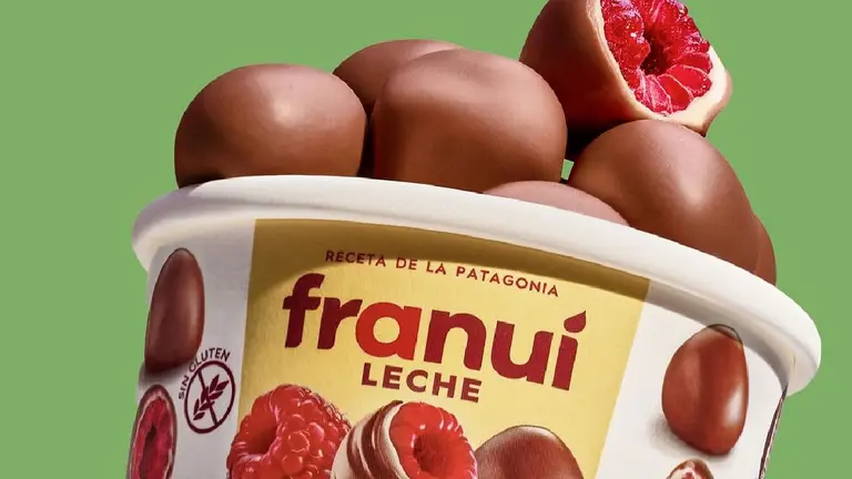 Pote de frambuesas Franui bañadas en chocolate con leche sobre un fondo verde