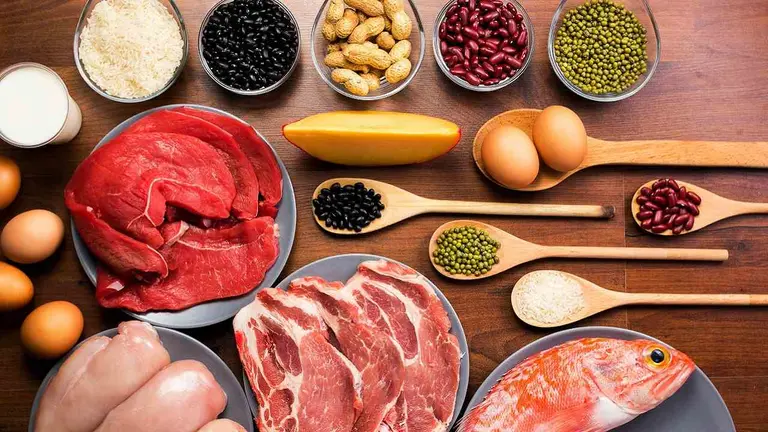 Alimentos con proteína, como carnes, legumbre, huevos y pescado, sobre una mesa