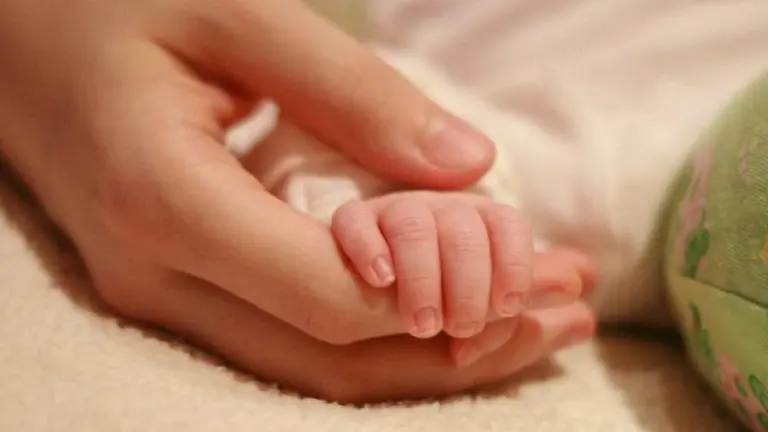 La mano de una mamá sosteniendo la mano de un bebé
