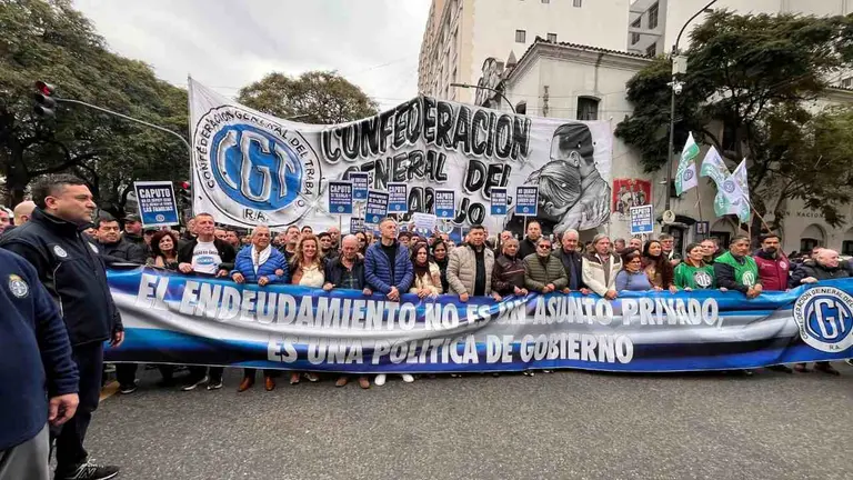 Un grupo de personas marchando por la calle, con banderas de la CGT y mensajes contra el endeudamiento familiar
