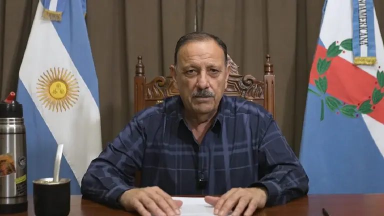 El gobernador Ricardo Quintela en un escritorio con una hoja entre y un mate y un termo al costado. Por detrás, la bandera argentina y la de La Rioja