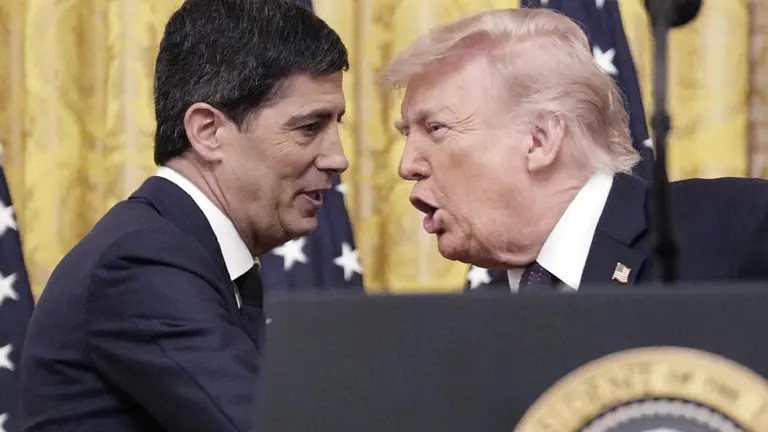 Kevin Warsh y Donald Trump se dan la mano con banderas norteamericanas de fondo