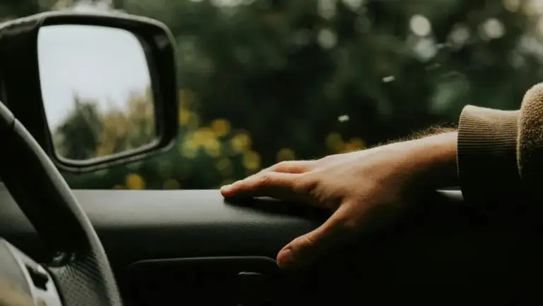 La mano de un pasajero apoyada sobre la puerta de un auto con la ventanilla baja