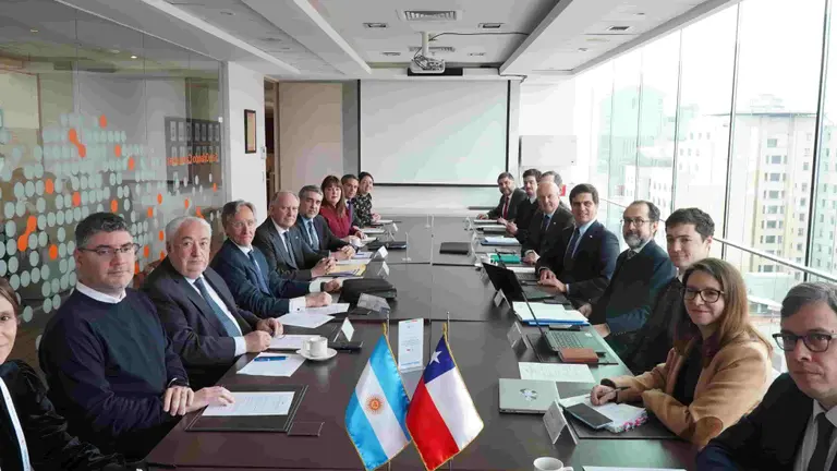 Funcionarios y empresarios reunidos en una larga mesa, con banderas de Argentina y Chile