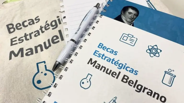 libro y bolsa de la beca manuel belgrano con lapicera retractil blanca