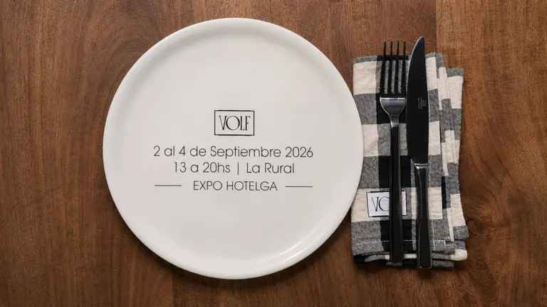 Vista cenital de una mesUn plato blanco de Volf, que anuncia su participación en Expo Hotelga 2026. A la derecha, un juego de cubiertos sobre una servilleta a cuadros (iProfesional)