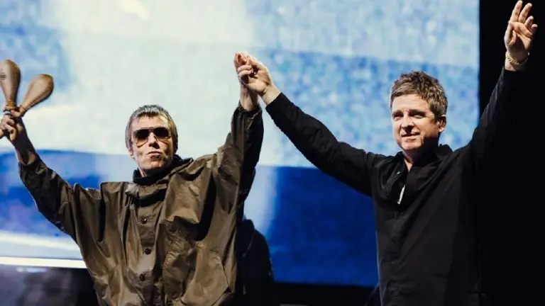 Los hermanos Liam y Noel Gallagher de Oasis agarrados de la mano en un recital