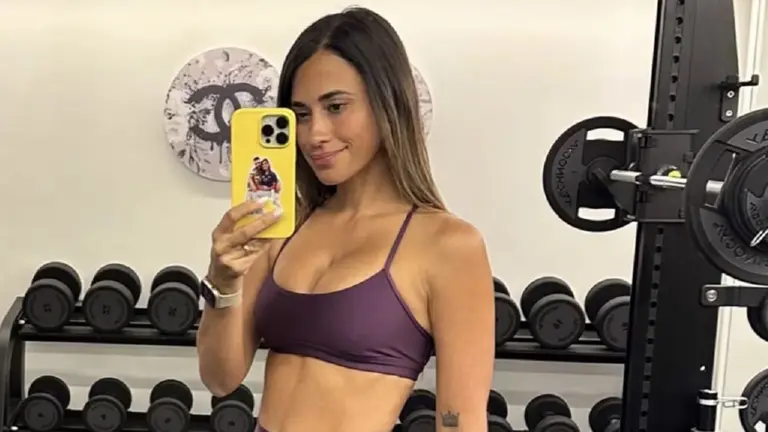 Antonela Roccuzzo en una sala con pesas y un celular en la mano