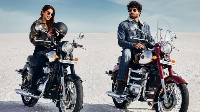 Una chica arriba de una moto jawa color negra con un casco en la mano y un chico al costado arriba de una moto color bordó en una salina