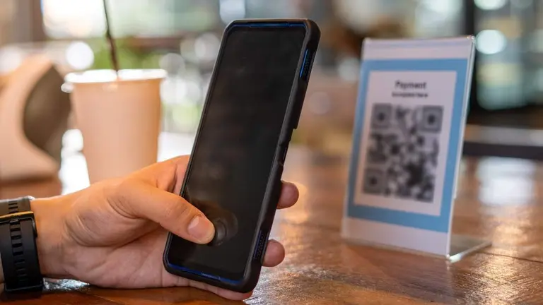 Persona pagando con el celular a través de un código QR en un comercio