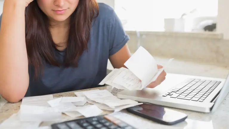 mujer preocupada con papeles y deudas en mano