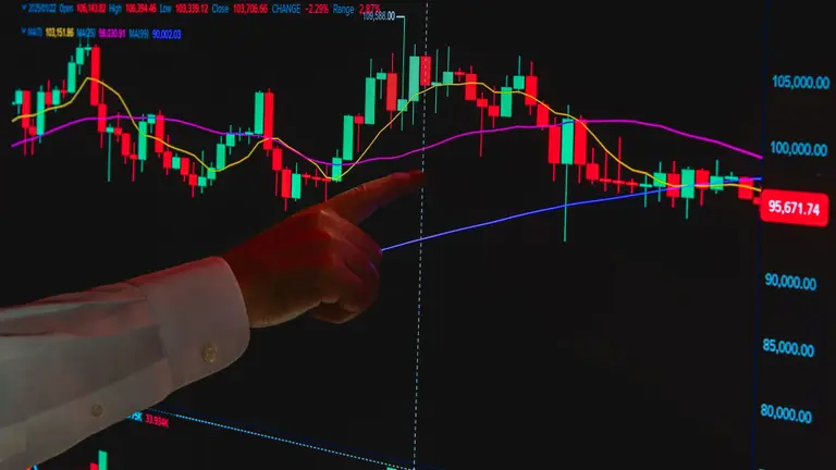 Invesor apunta con su dedo a una pantalla con el gráfico de la cotización de Bitcoin