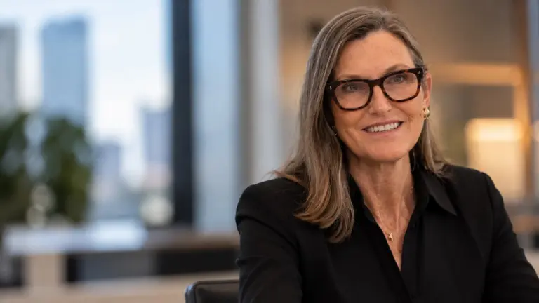 Cathie Wood, CEO de ARK Invest, posa con anteojos de marco oscuro y camisa negra en una oficina